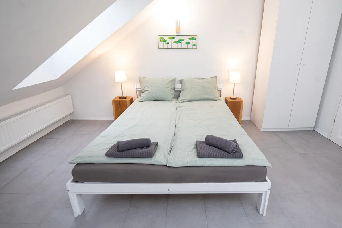 Double bed with oak bedside tables and reading lamps in the Woody 1 attic studio, Zagreb