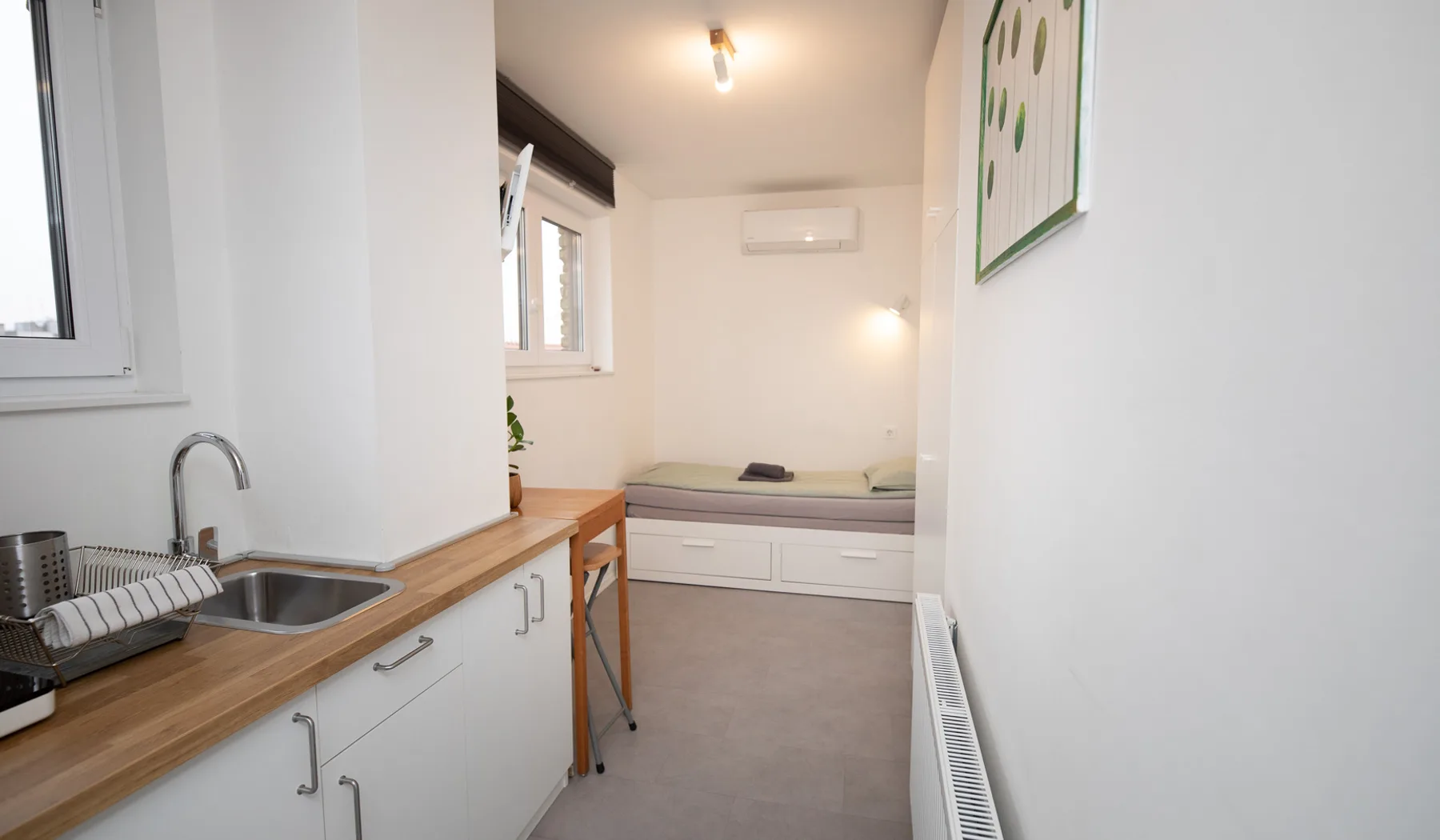 Woody 3 compact studio apartment in Zagreb with a galley kitchenette, bar table and bed in an alcove