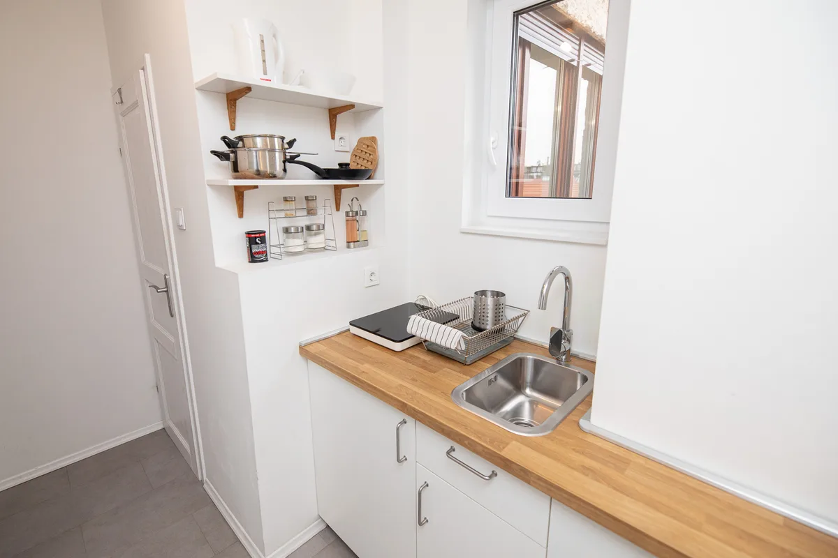 Galley kitchenette with open shelves, kettle, pans and a portable induction hob in Woody 3, Zagreb