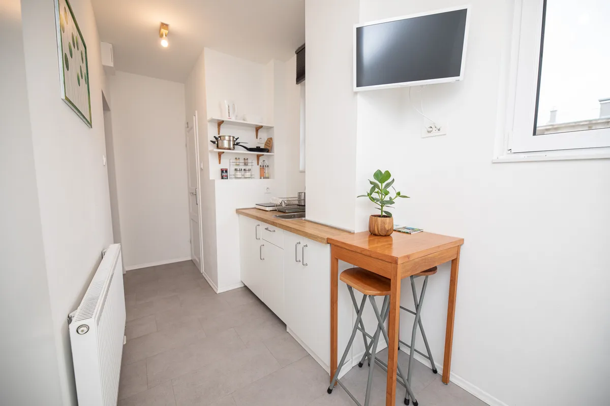 Living and dining area with a bar table, folding stools and wall-mounted TV in Woody 3, Zagreb
